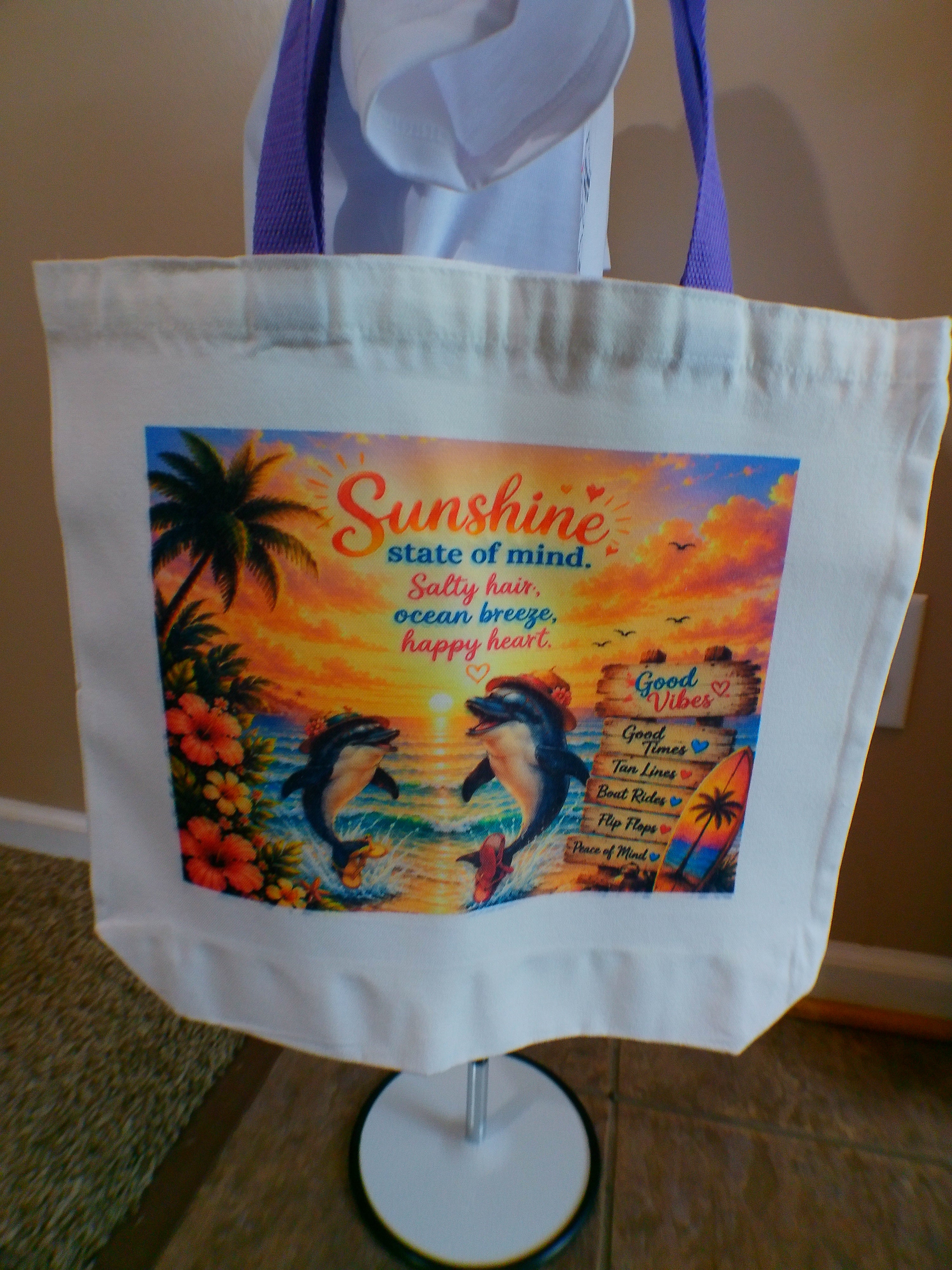 White canvas tote bag with purple handles and Sunshine State of Mind dolphin sunset design
